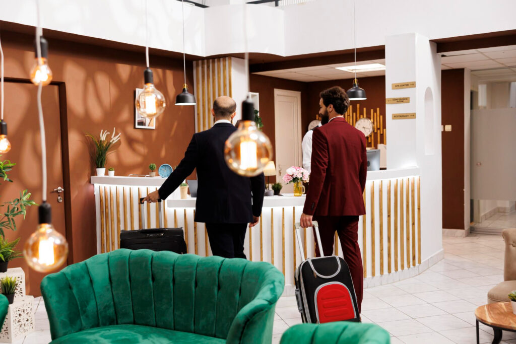 Couple ou clients entrant dans le hall d’un hôtel de charme, accueillis dans une atmosphère élégante